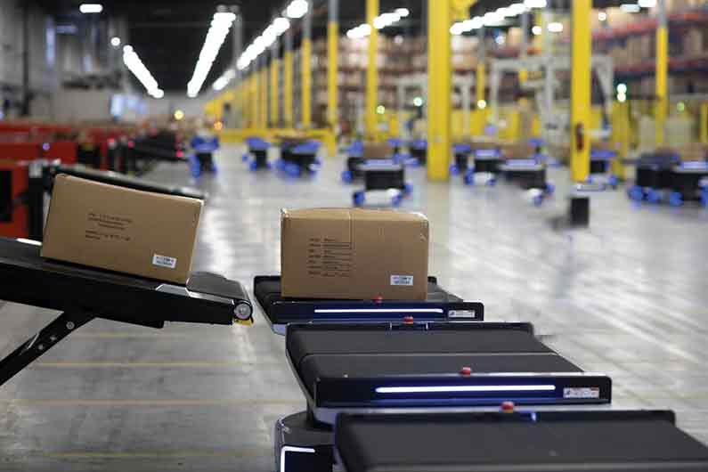 automated inbound conveyor moving carton to autonomous warehouse robot.
