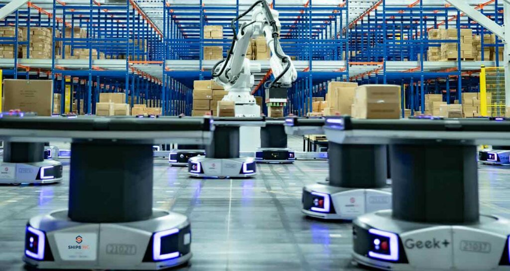 Automated warehouse robots in front of robotic arm