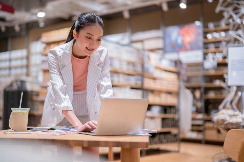 young woman working in warehouse on laptop